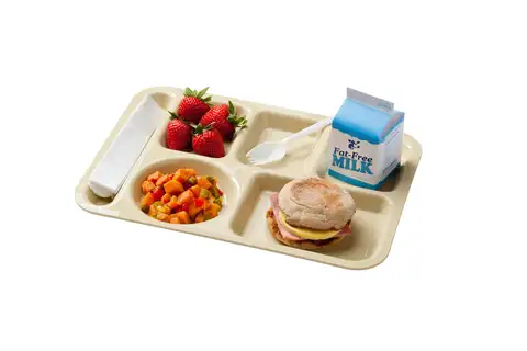A beige cafeteria tray holding strawberries, diced sweet potatoes and peppers, a ham, egg and cheese English muffin sandwich, a carton of fat-free milk, a napkin and a plastic spork